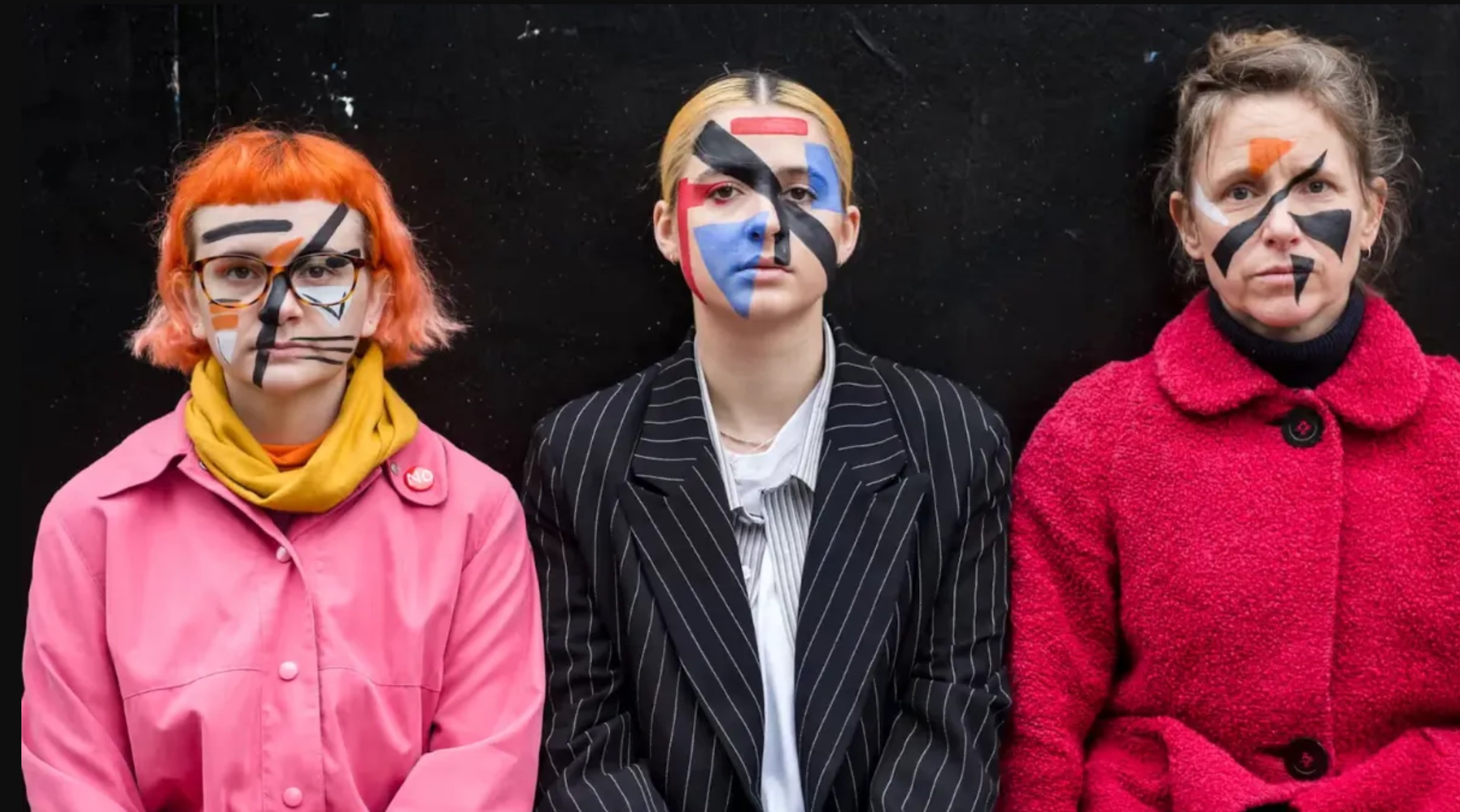 Three activists wearing geometric face-paint, called “razzle dazzle